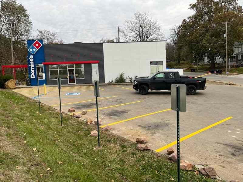 A black truck is parked in front of a domino 's pizza restaurant.