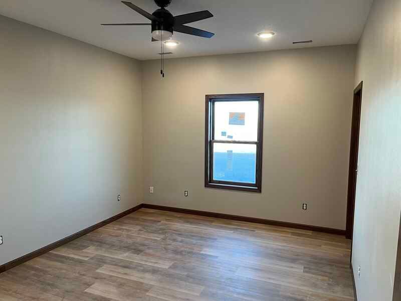 An empty room with a ceiling fan and a window.