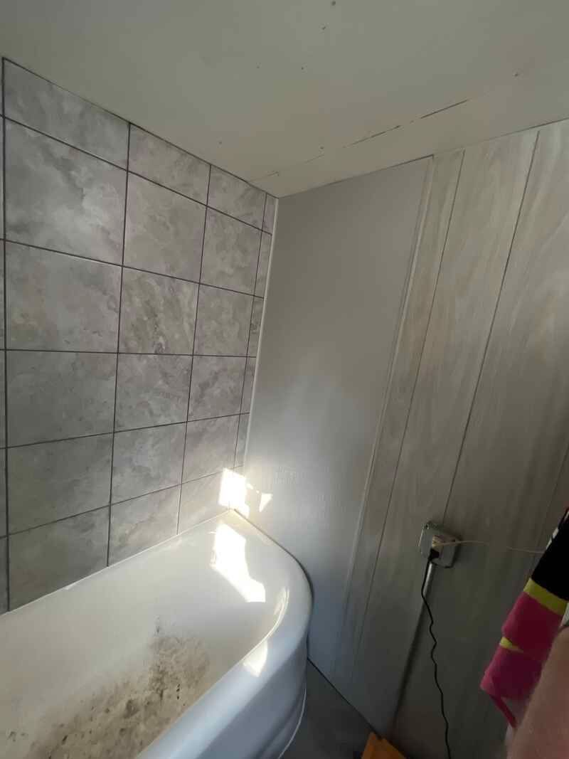 A bathroom with a bathtub and tiled walls.