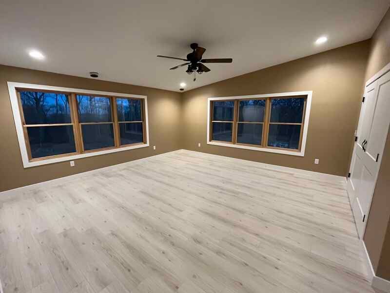 An empty living room with a ceiling fan and lots of windows.
