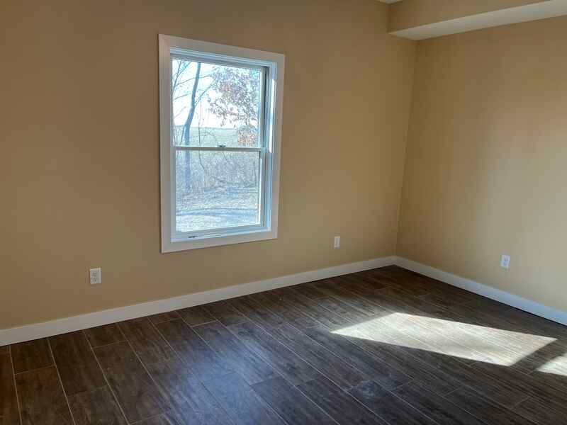 An empty room with hardwood floors and a window.