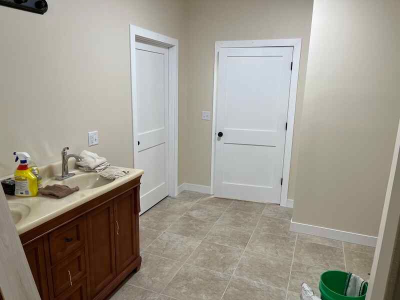 A bathroom with a sink and a green bucket on the floor.