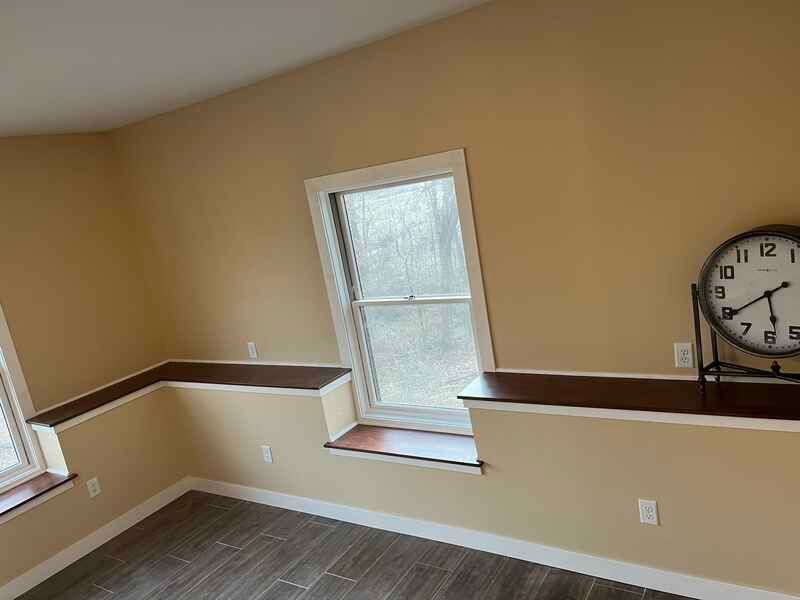 A room with two windows and a clock on the wall.