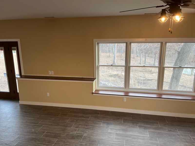 An empty living room with a ceiling fan and two windows.