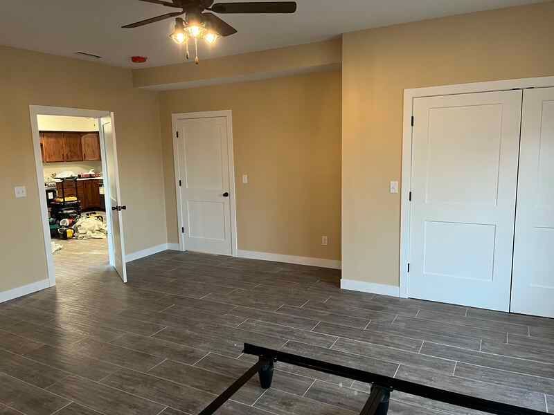 An empty living room with a ceiling fan and a bed frame.