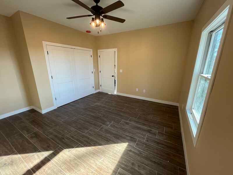 An empty bedroom with a ceiling fan and a window.