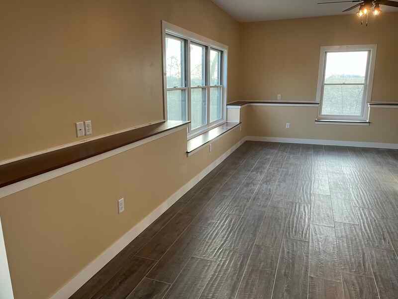 An empty living room with hardwood floors and a ceiling fan.