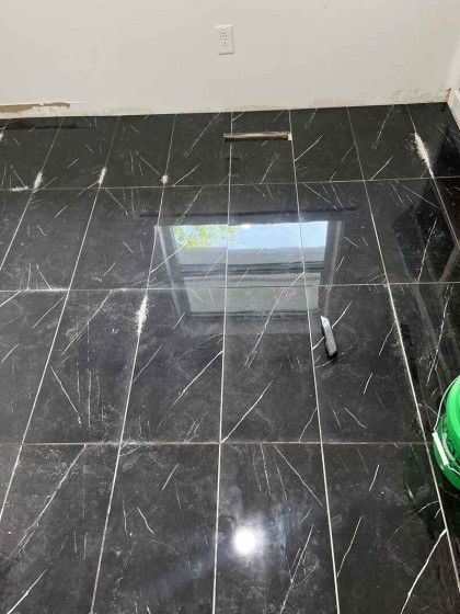 A black tile floor with a window reflected in it.