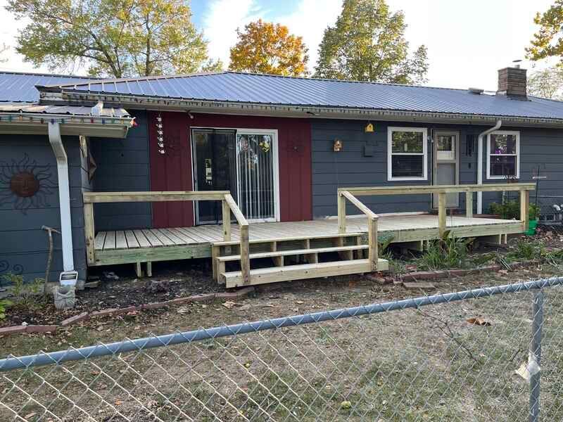 A house with a wooden deck and stairs in front of it.