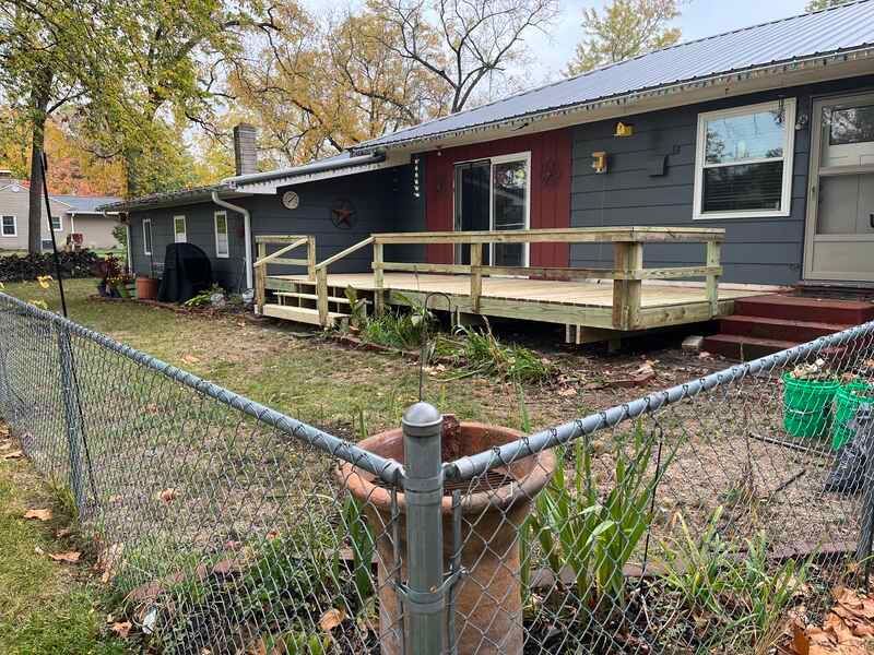 A house with a wooden deck behind a chain link fence.