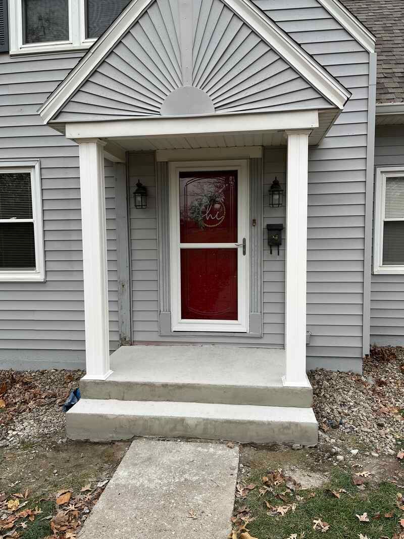 A gray house with a red door and a porch.