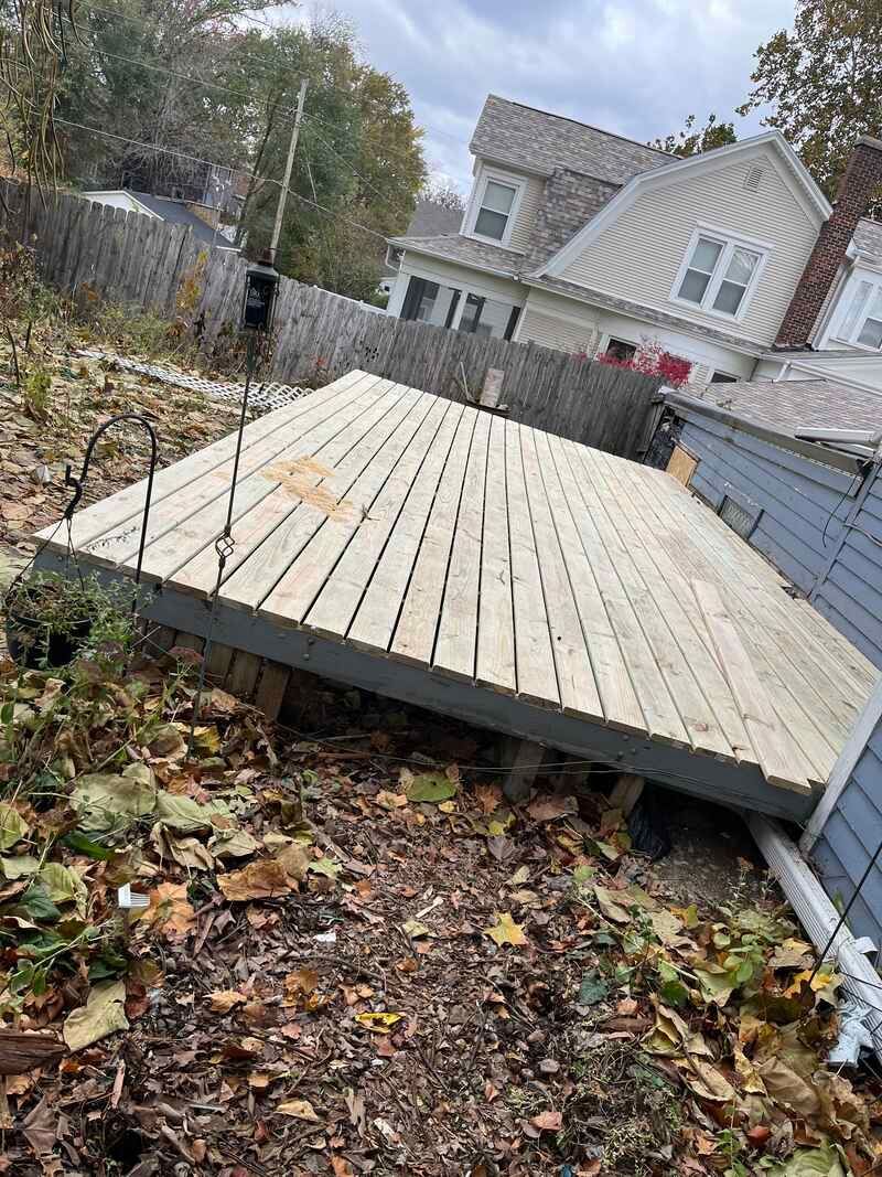 A wooden deck is sitting on the ground in front of a house.