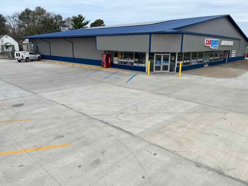 A large building with a blue roof and a parking lot in front of it.