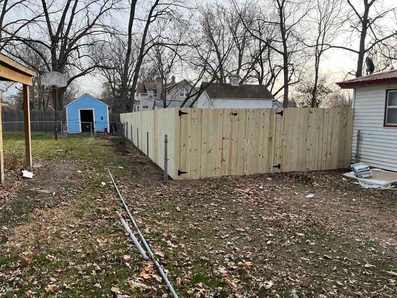 A wooden fence is in the backyard of a house.