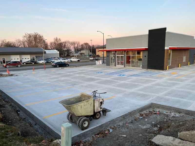 A dump truck is parked in a parking lot in front of a building under construction.