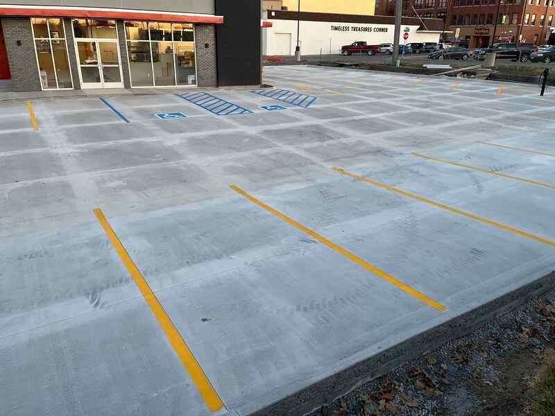 A concrete parking lot with yellow lines in front of a building.