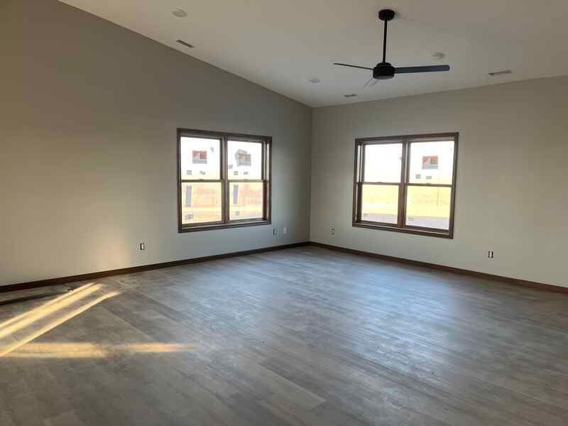 An empty living room with hardwood floors and a ceiling fan.