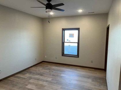 An empty room with a ceiling fan and a window.