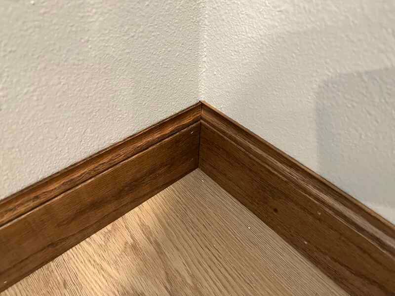 A corner of a room with a wooden floor and a white wall.