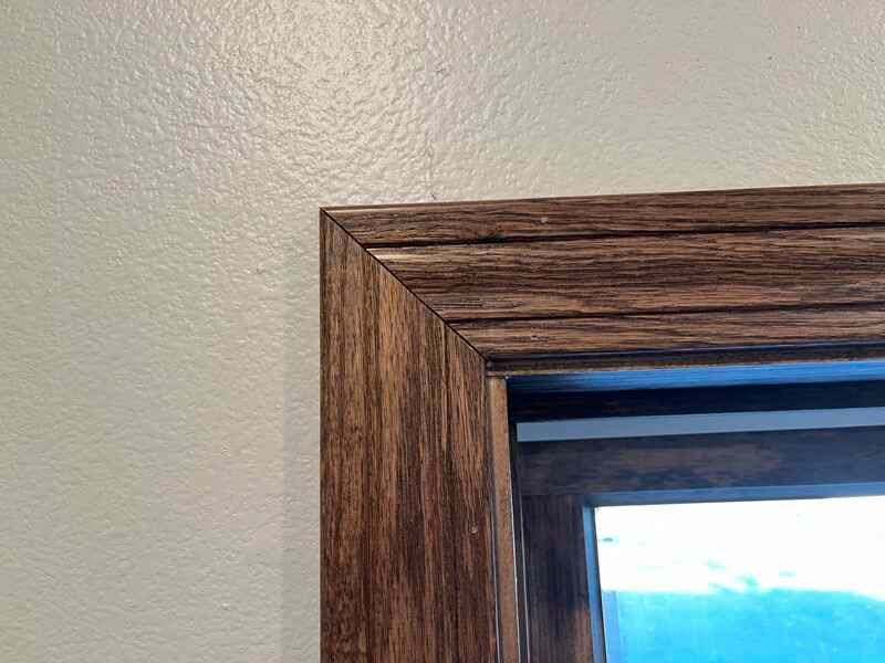 A close up of a wooden window frame on a white wall.