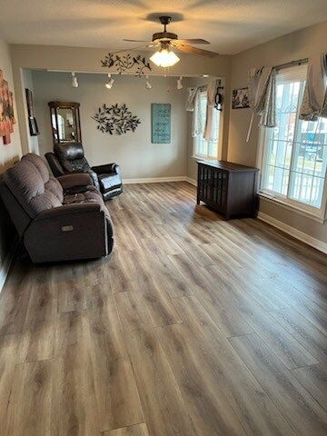 A living room with hardwood floors and a ceiling fan.