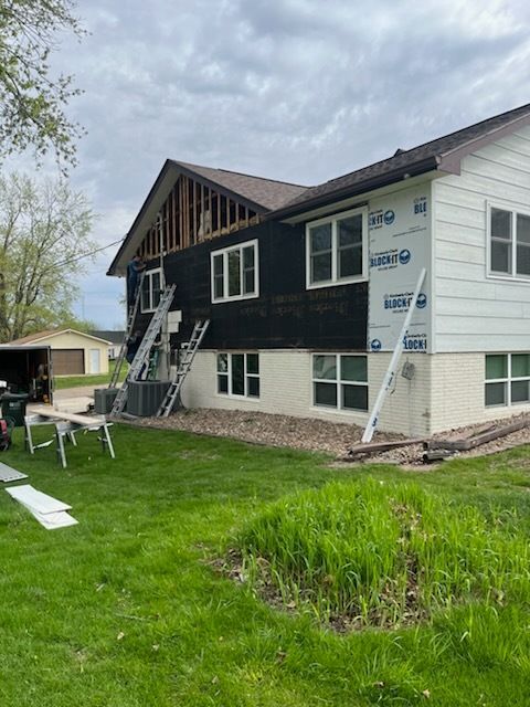 A house is being remodeled with a black siding and white trim.