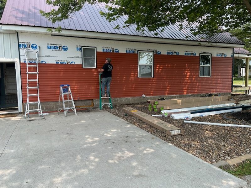 A man is standing on a ladder on the side of a building.