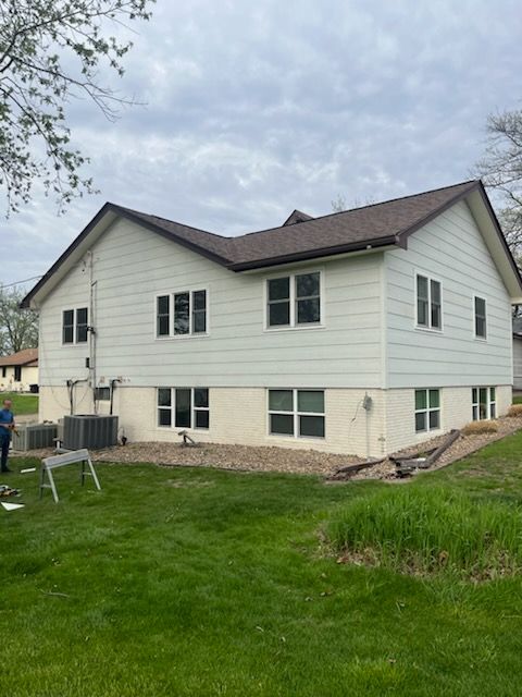 A white house with a brown roof and a lot of windows