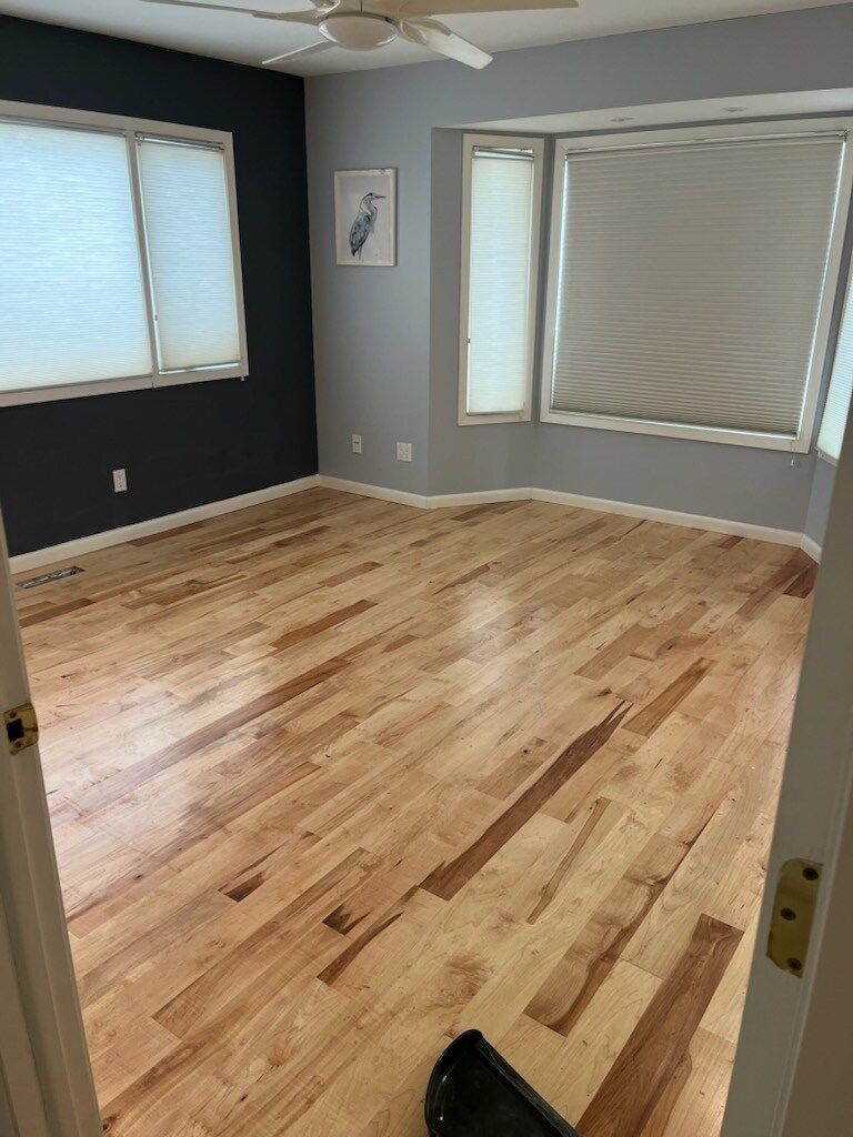 A bedroom with hardwood floors and a ceiling fan.