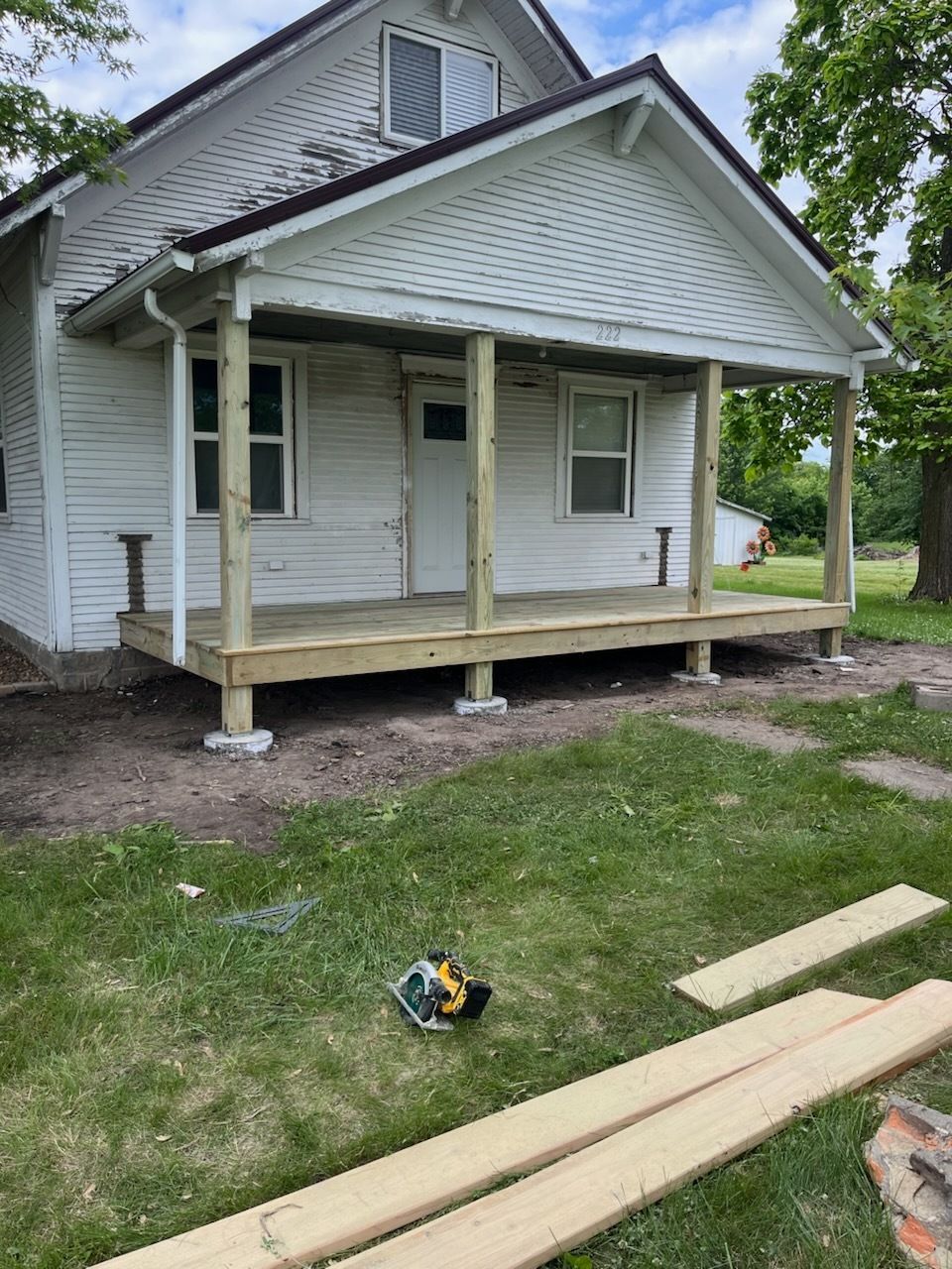 A white house with a wooden porch is being built.