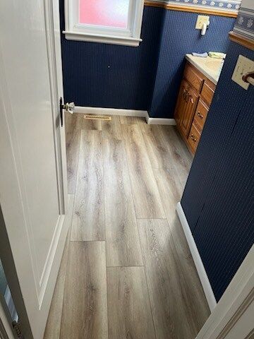 A bathroom with hardwood floors and blue walls.