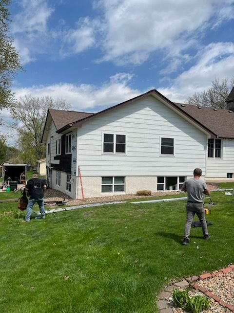 Two men are standing in front of a white house.