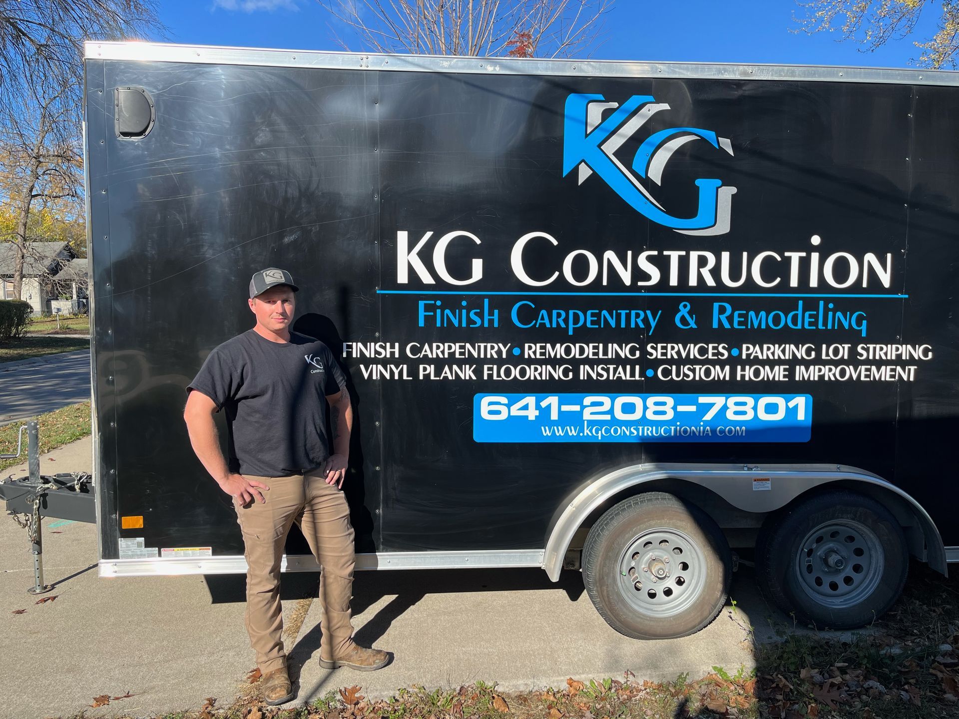 A man standing in front of a trailer that says kg construction