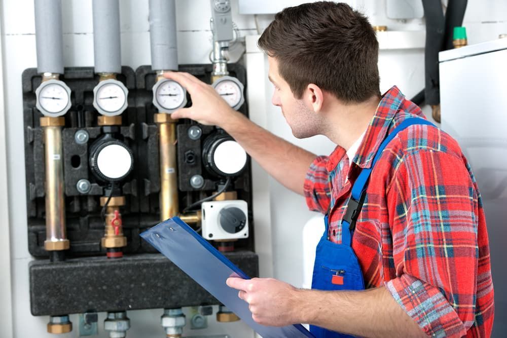 Technician Inspecting Heating System Gauges While Holding Clipboard — SOS Hot Water & Plumbing Services in Kiama, NSW