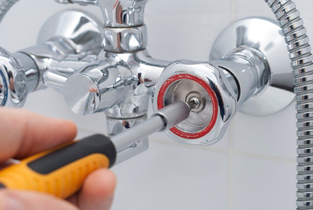 Plumber Using Screwdriver to Repair a Bathroom Faucet Handle — SOS Hot Water & Plumbing Services in Kiama Downs, NSW