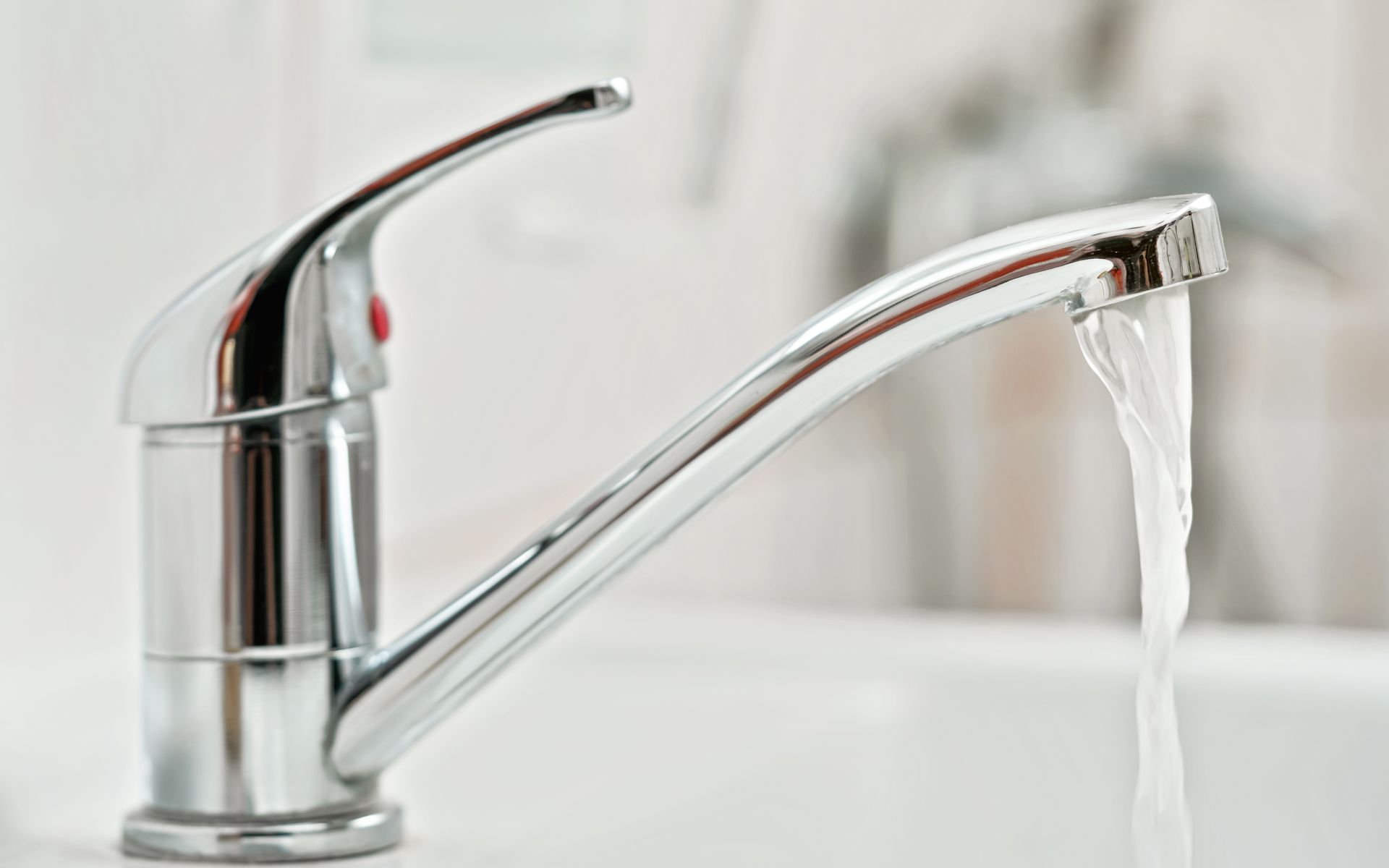 A chrome kitchen tap running water into a sink basin in a modern home.
