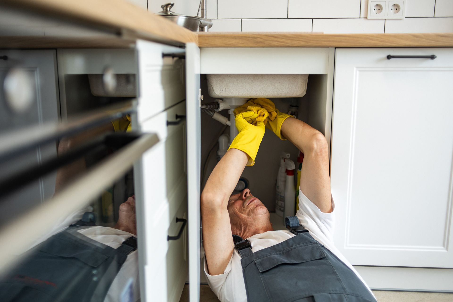 A plumber fixing the sink in the kitchen.