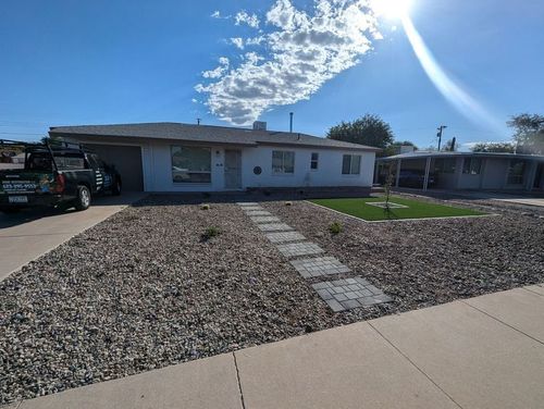 A white house with a paver walkway and turf.