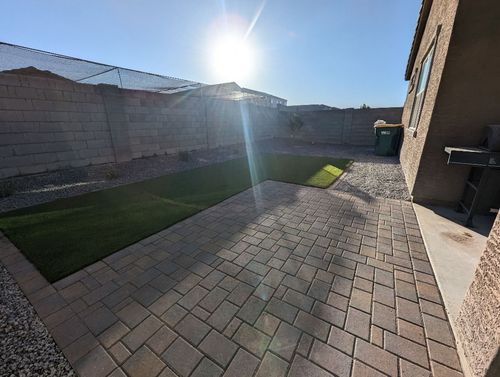 The sun is shining in a backyard with pavers.