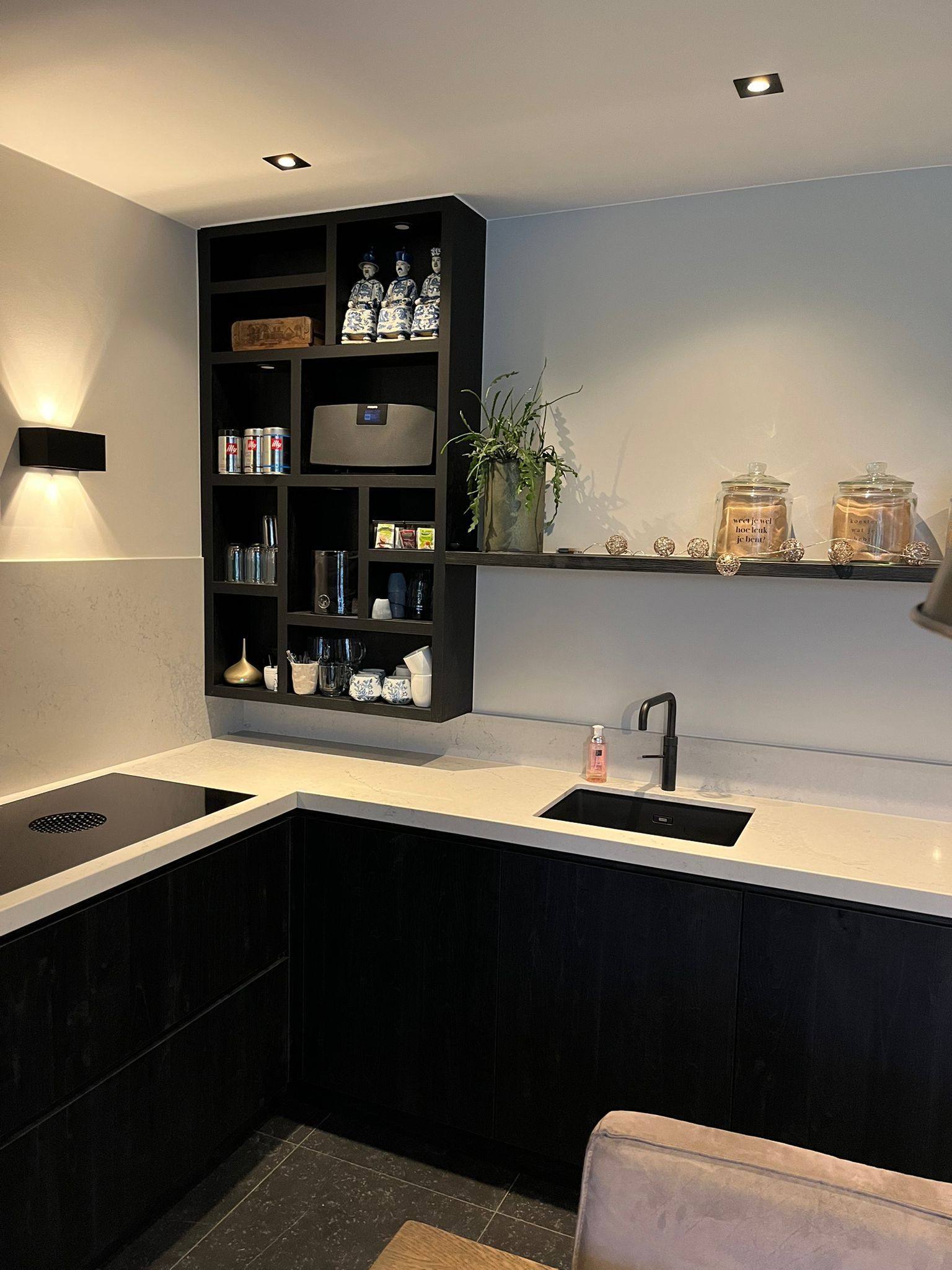 Moderne keuken met zwarte kasten, open planken met spullen en een spoelbak.