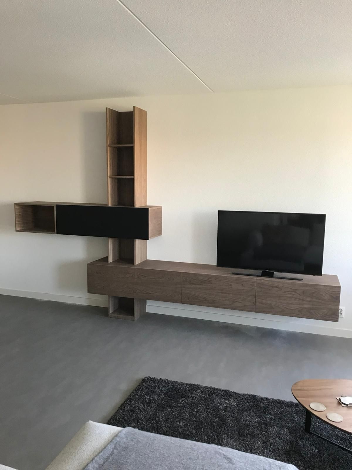 Modern zwevend entertainmentcentrum met tv, planken en kasten in de woonkamer.