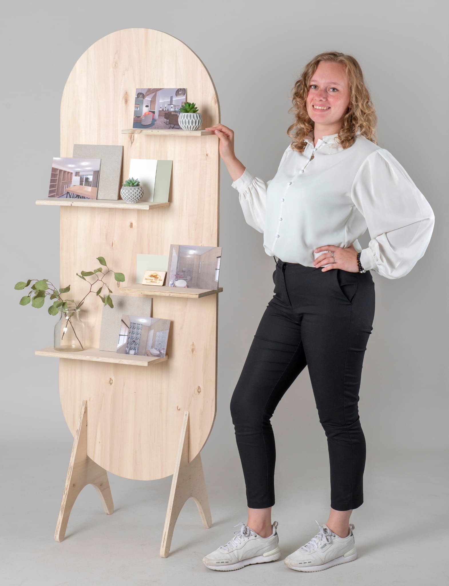 Een vrouw staat bij een houten plank waarop spullen staan ​​uitgestald.