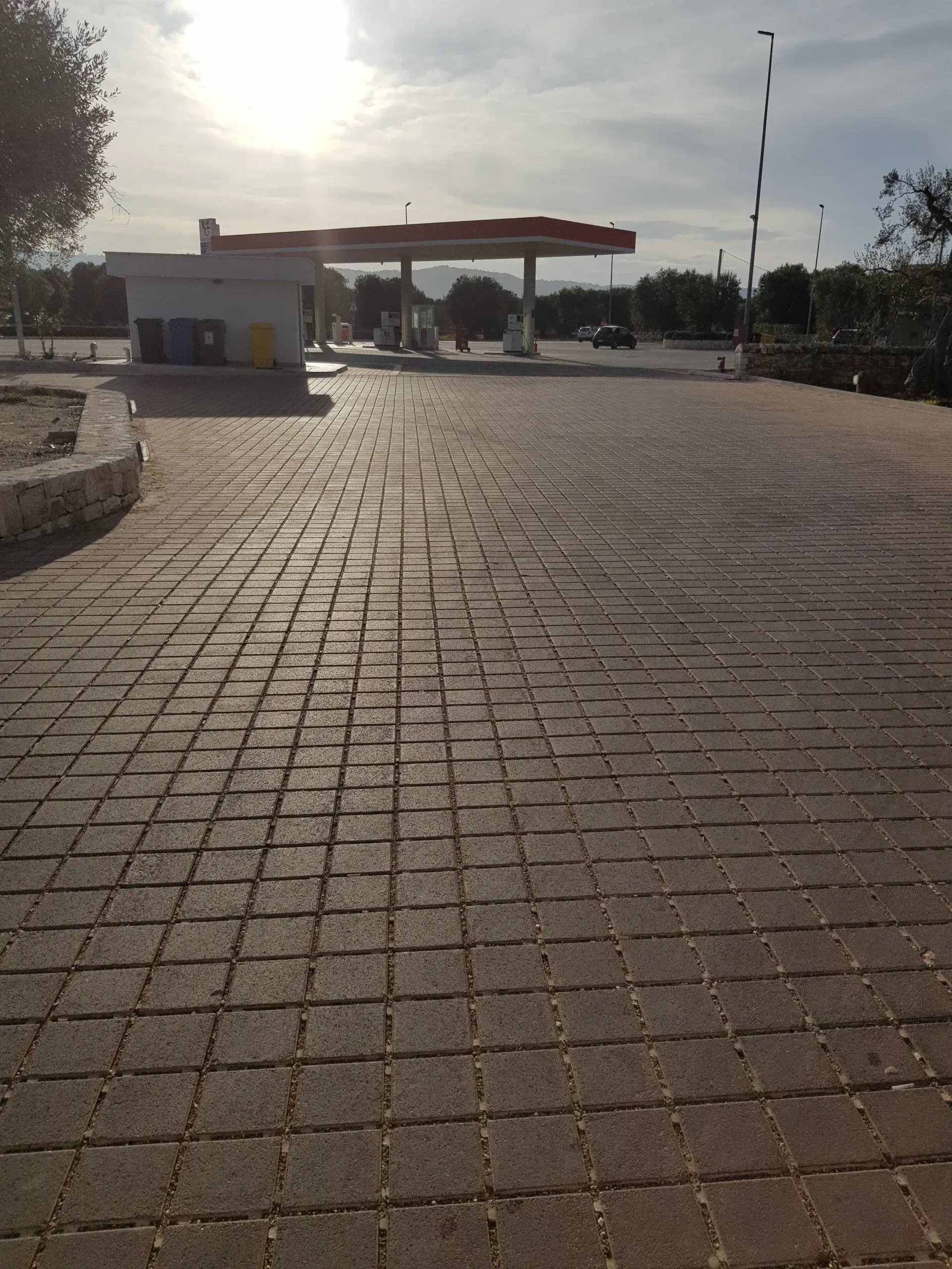 Stazione di servizio con pavimentazione in mattoni sotto un cielo luminoso.