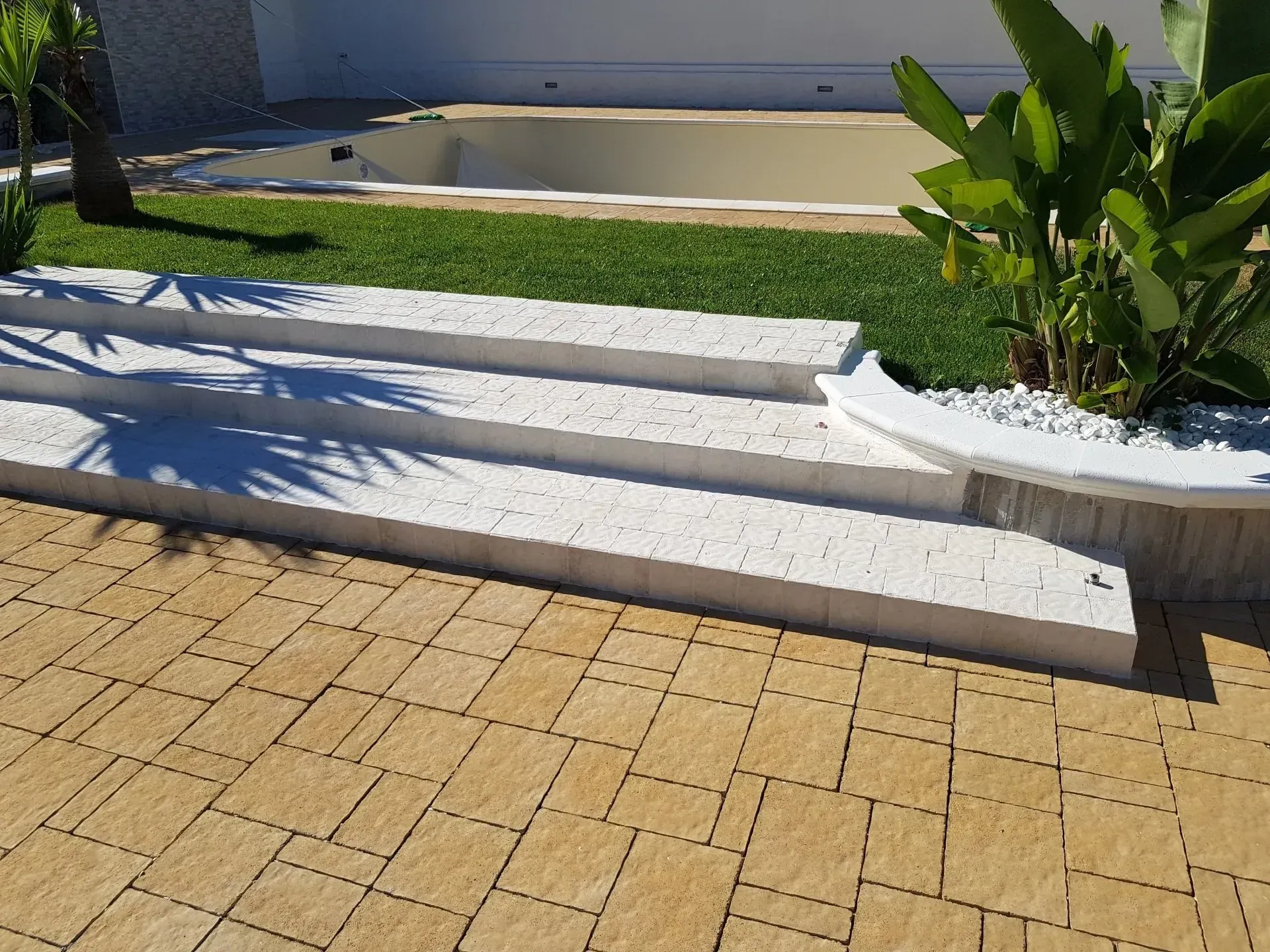 Gradini in pietra chiara che conducono alla piscina e al prato.