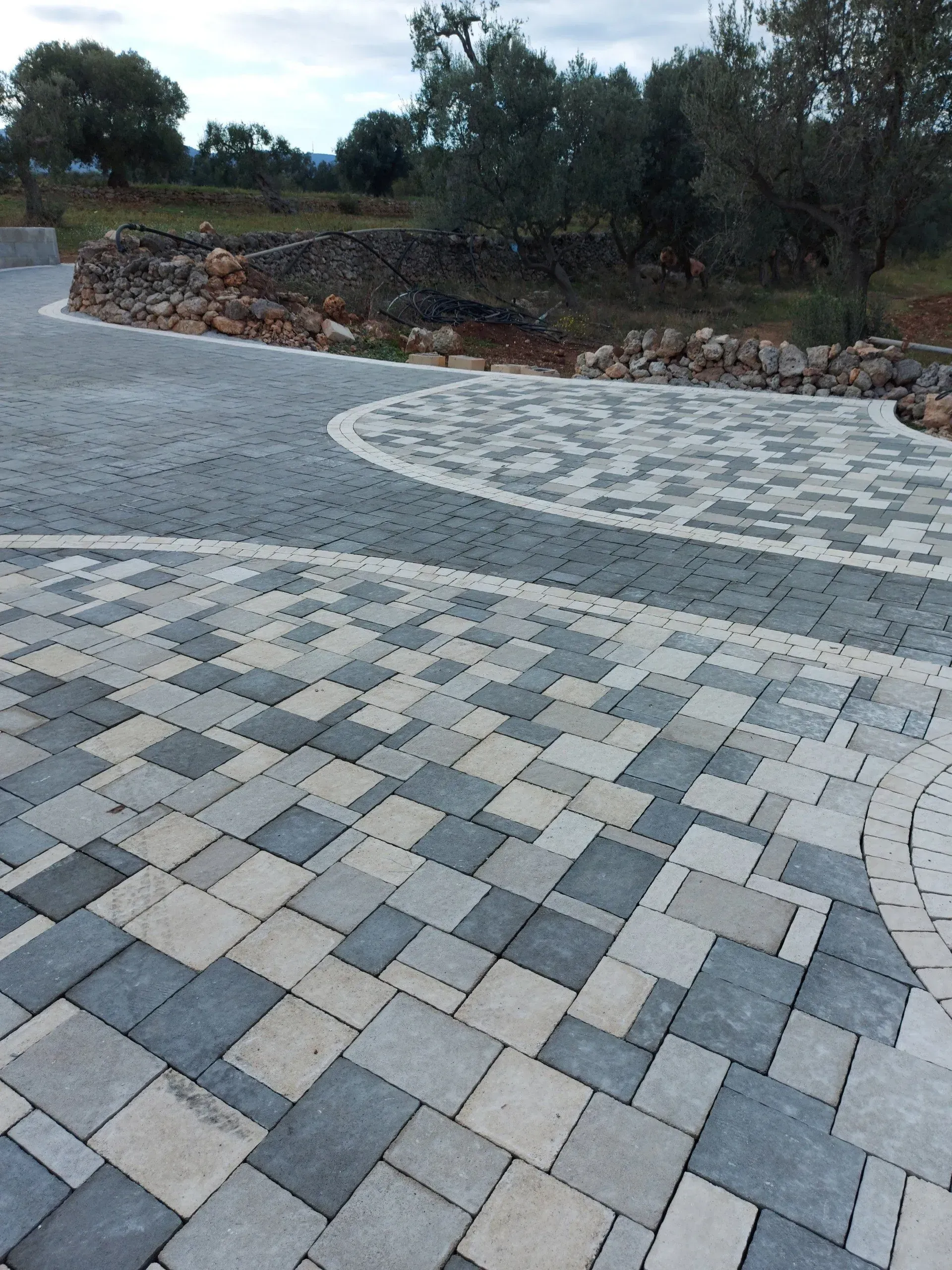 Vialetto pavimentato con blocchi quadrati alternati di colore grigio e crema, disposti secondo un disegno a motivi.