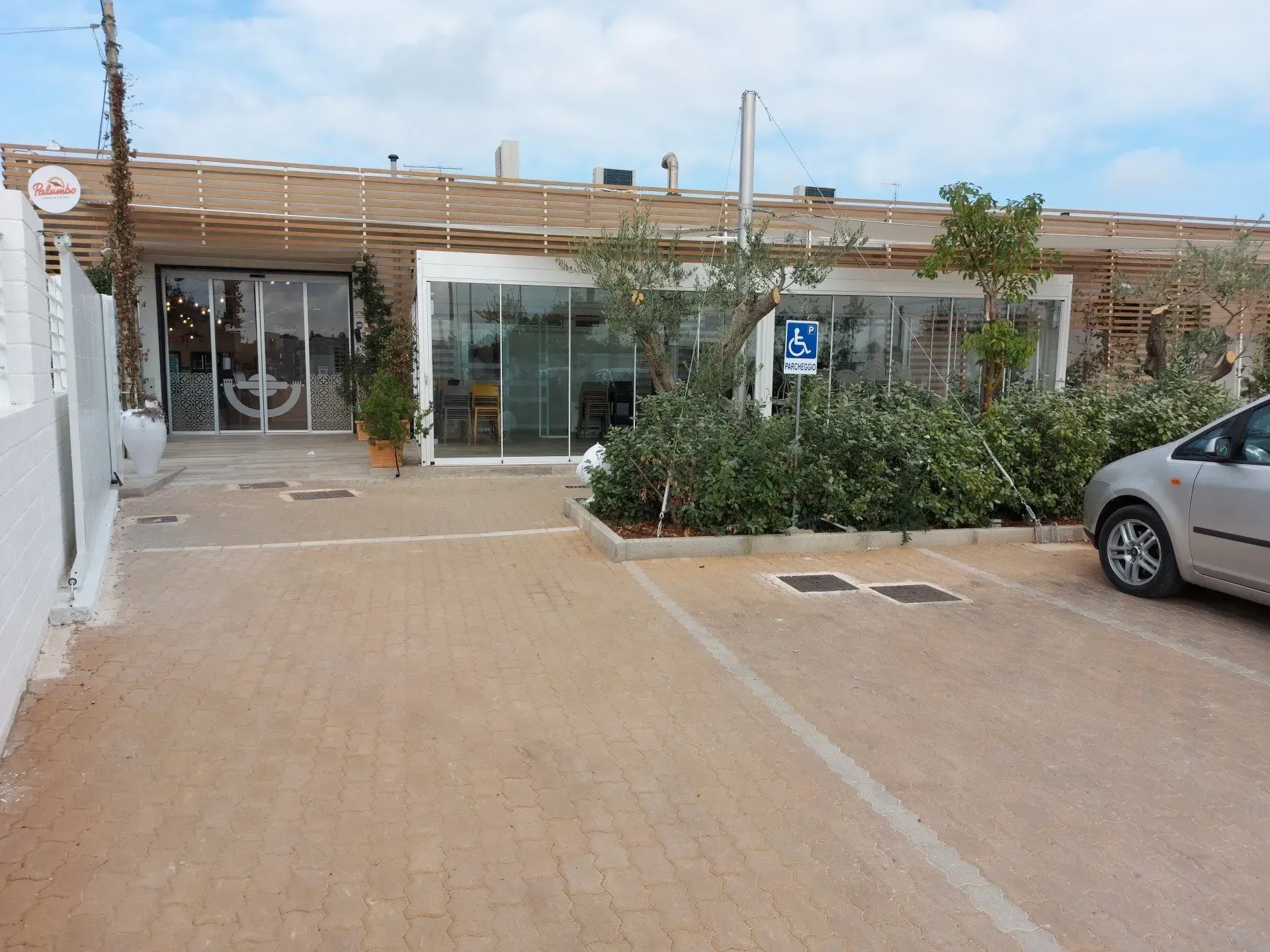 Ristorante con vetrate, parcheggio accessibile e tetto ricoperto di bambù.