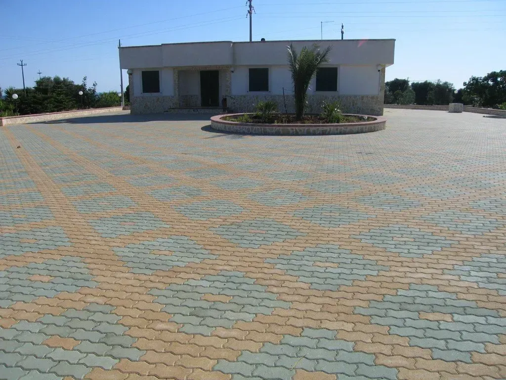 Un piccolo edificio bianco con un vialetto asfaltato in un ambiente rurale.