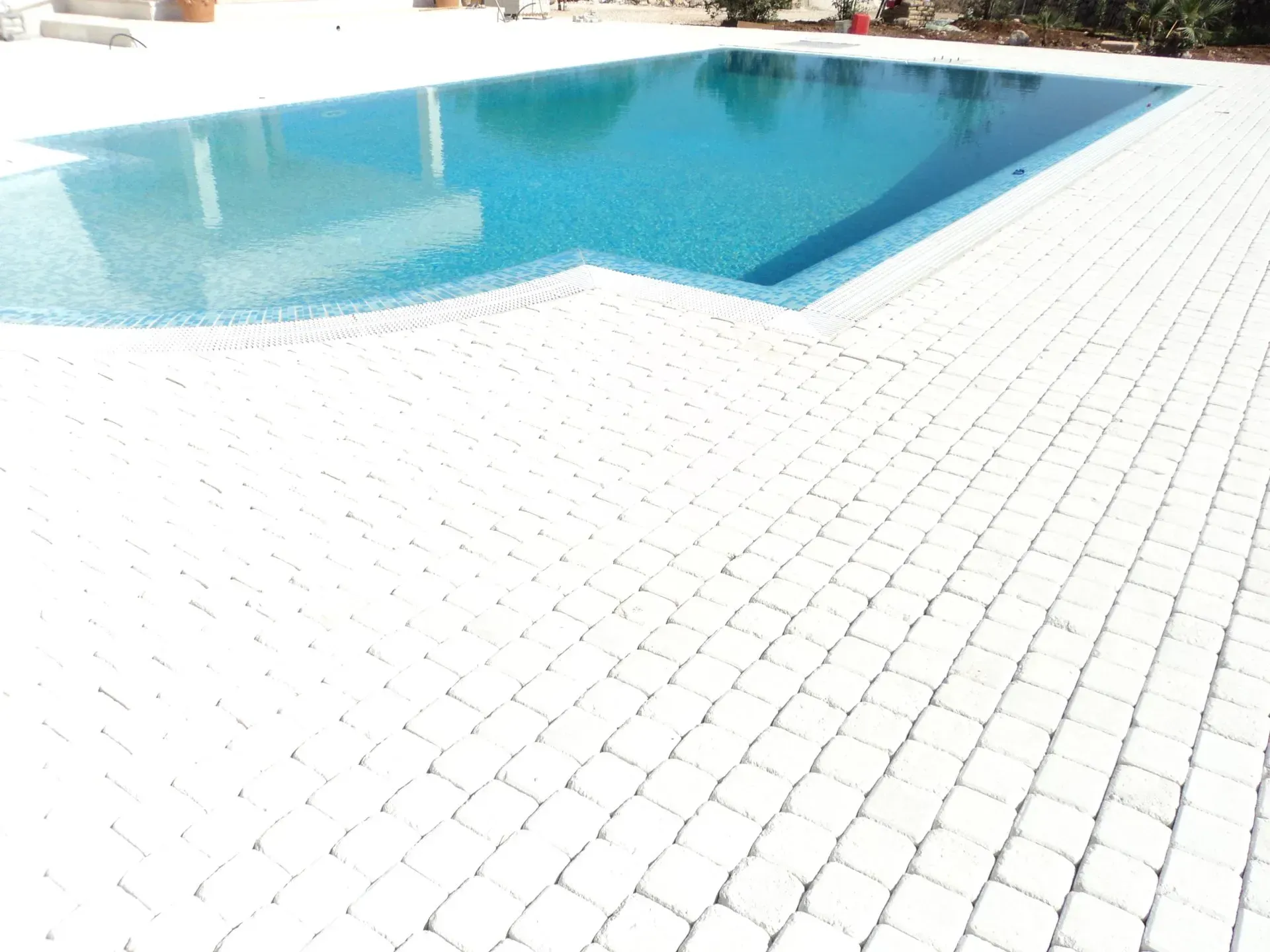 Piscina con acqua cristallina e rivestimento piastrellato bianco.