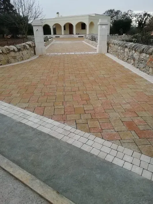 Vialetto lastricato in mattoni che conduce a un edificio color crema con muri e bordatura in pietra.