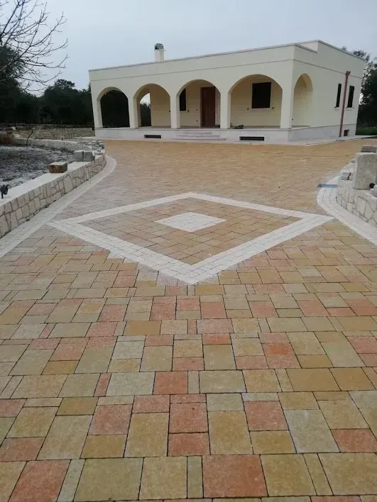 Vialetto lastricato che conduce a una casa bianca con archi e una porta marrone.